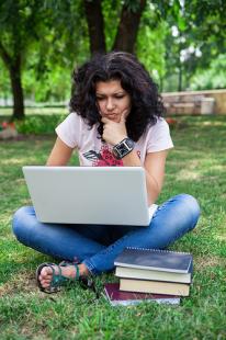 Young woman elearning on a laptop outside